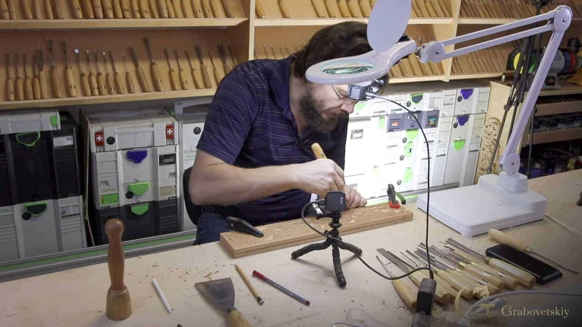 Bent under the magnifier lamp, tool racks behind
