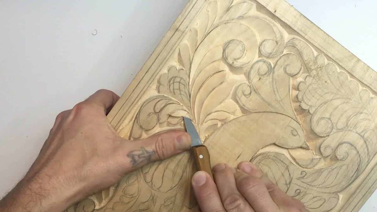 One hand steadies the work while the other runs a blade down a leaf already cut