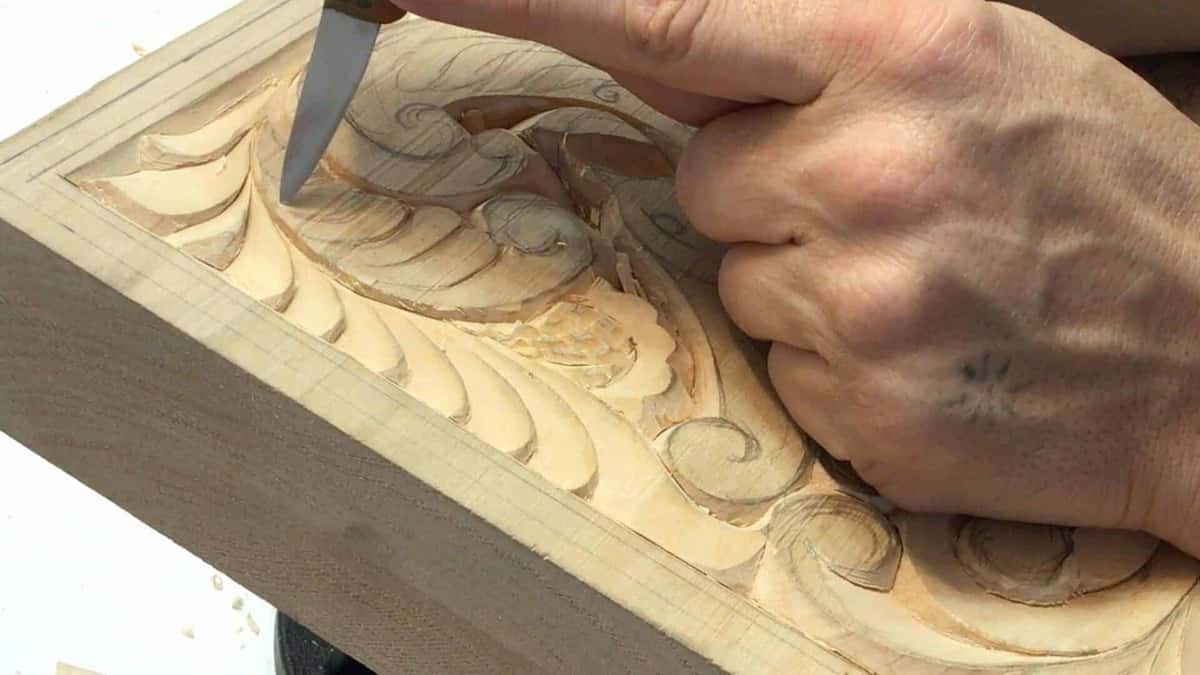 Knife lifts a chip from the board edge, dry fibers parting clean