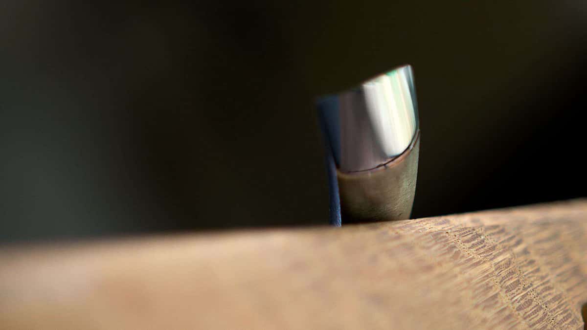 Macro view of a bright gouge edge, the thin line of steel that a dense board destroys quickly