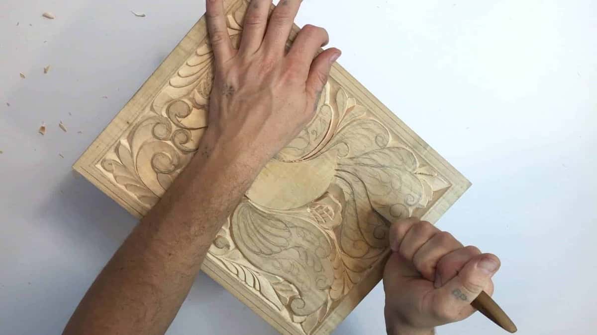 Flat hand steadying a carved panel