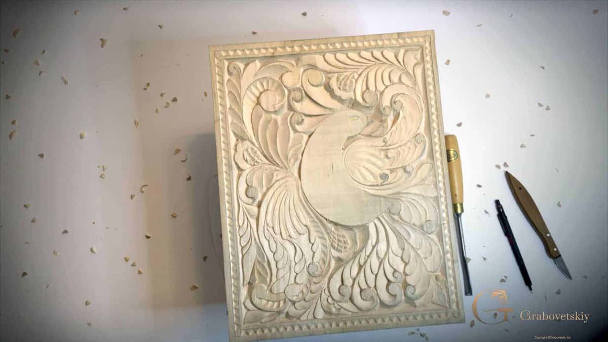 Bare pale relief panel lying beside two carving tools