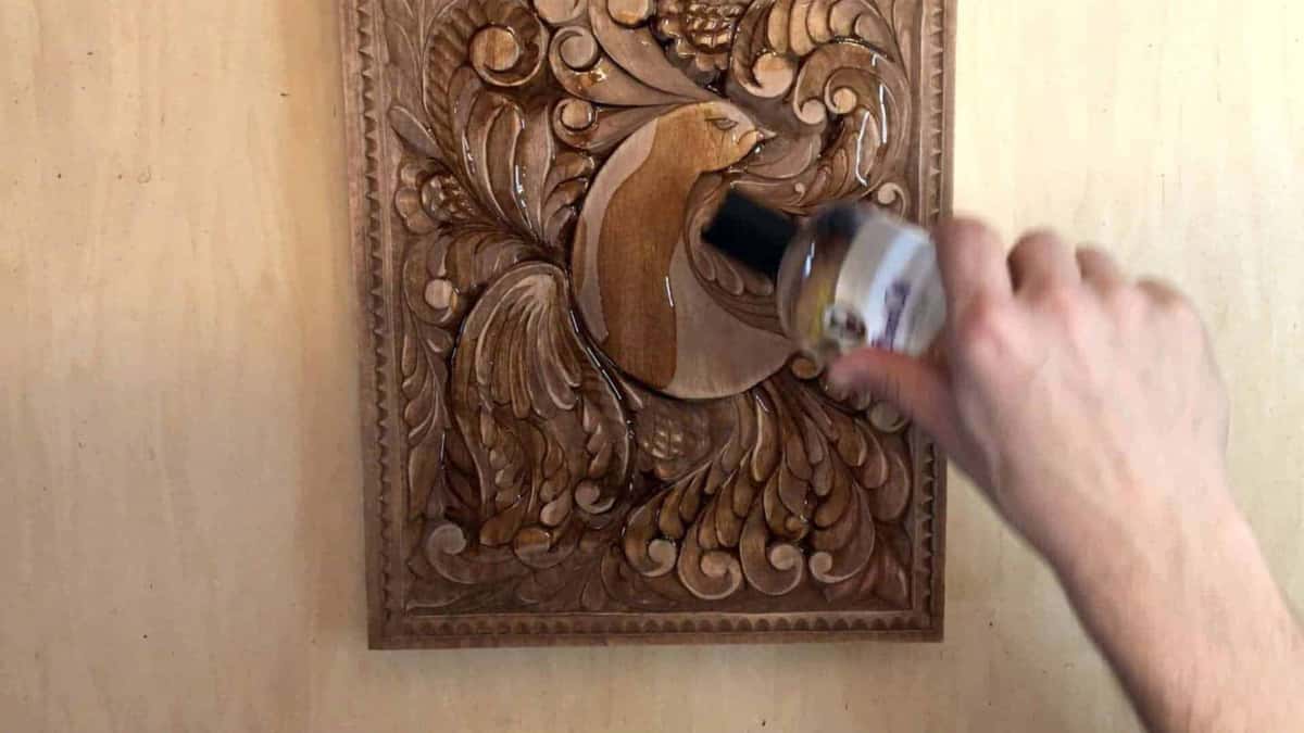 Oil poured straight onto the carved panel, pooling in the deep hollows
