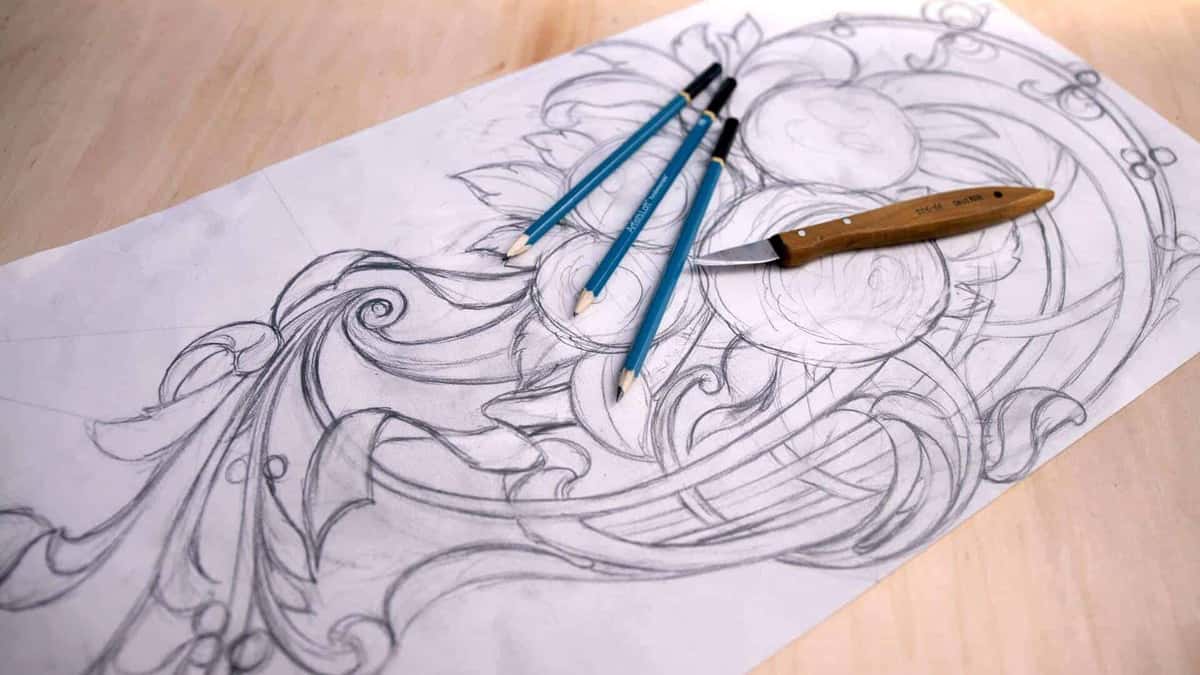 Full size drawing in pencil on paper, three blue pencils and a carving knife lying on top.