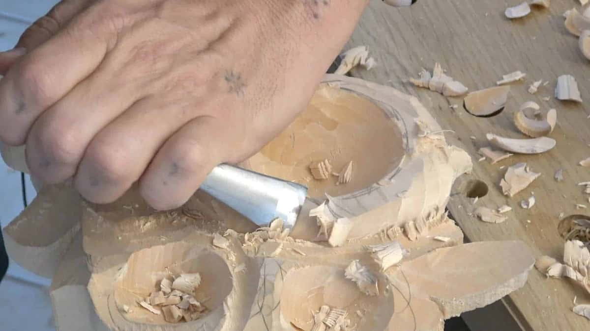 A wide flat chisel driven by hand pressure alone through the hollowed petals of pale basswood