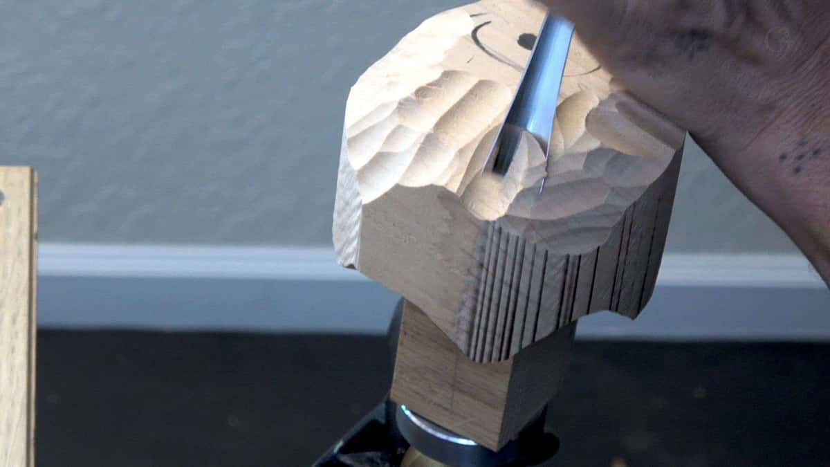 A square blank roughed to a dome, saw kerfs down the sides, gouge parked in the wood.