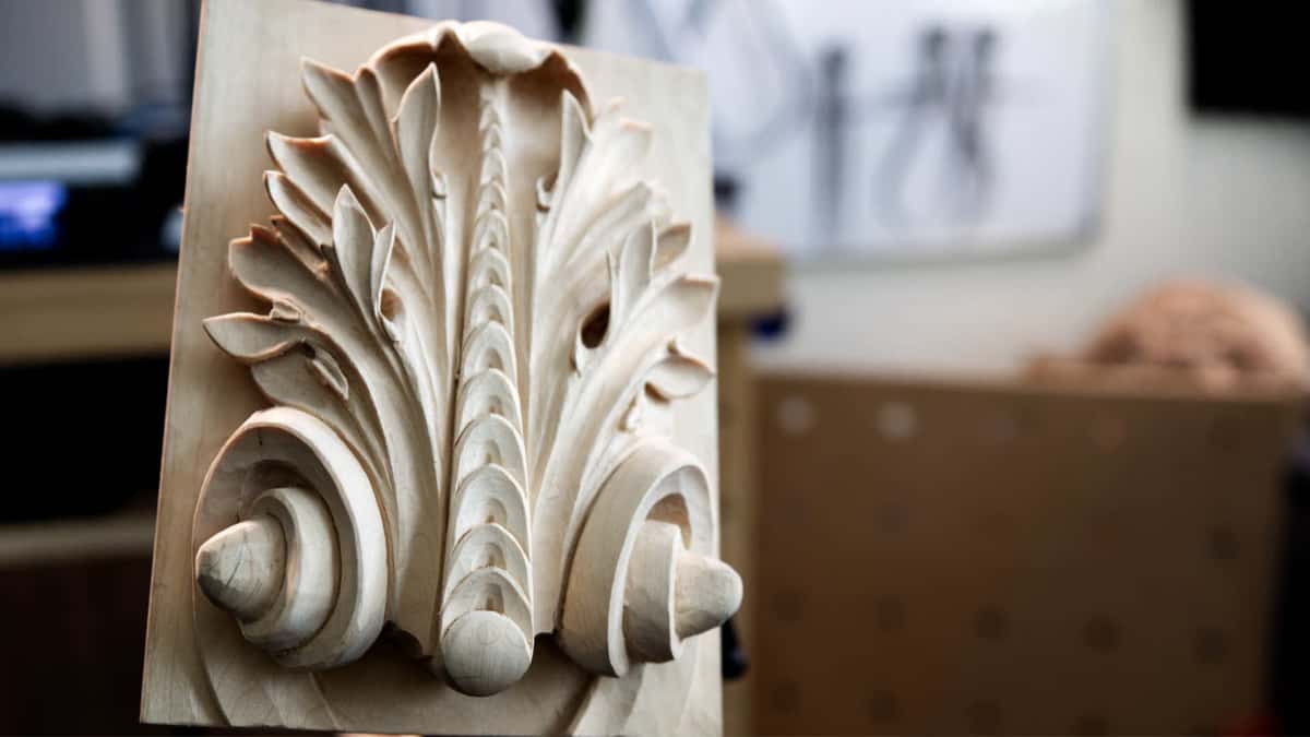 Soft even light rolling across a completed acanthus carving, the wood still bare.
