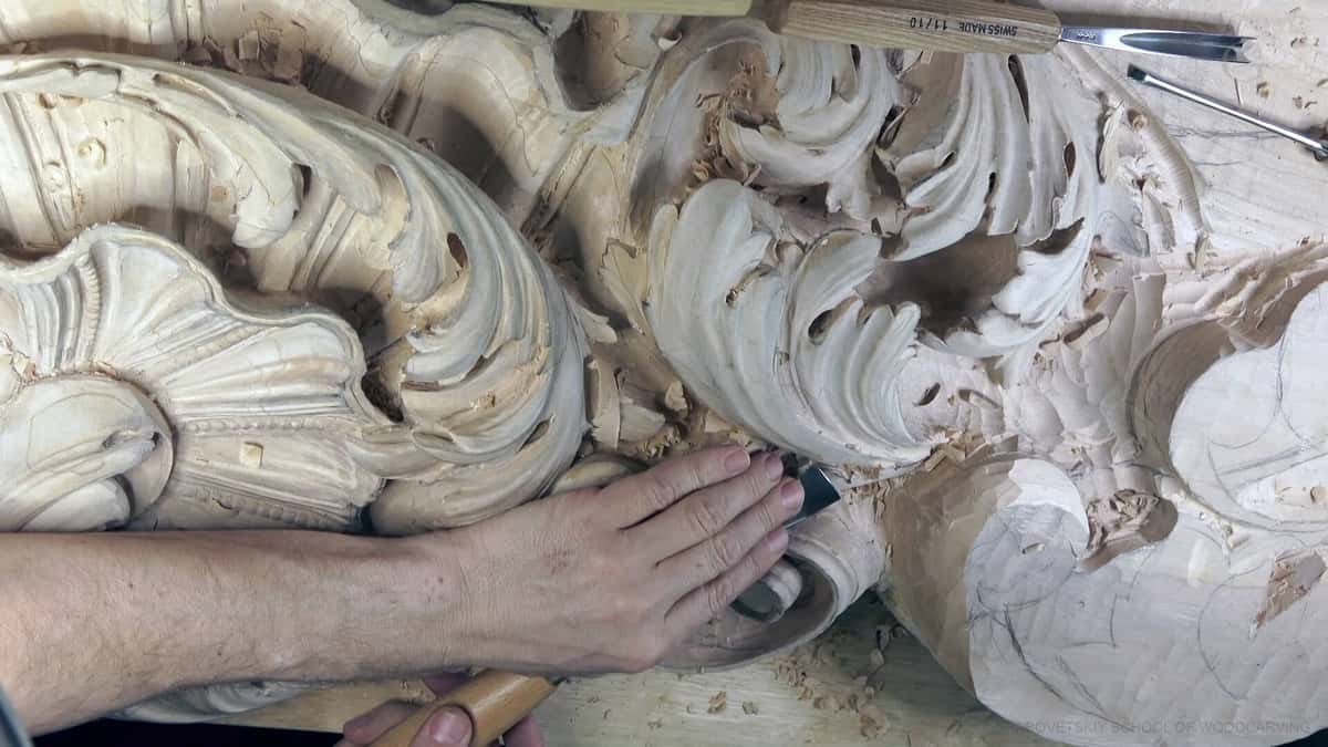 Deep limewood acanthus scrolls under a flat hand