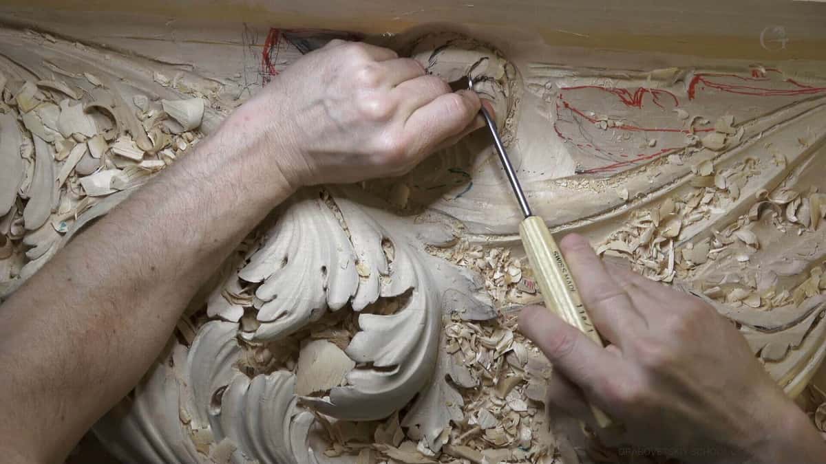 Pale limewood acanthus in deep relief, worked by two hands among red and blue layout marks