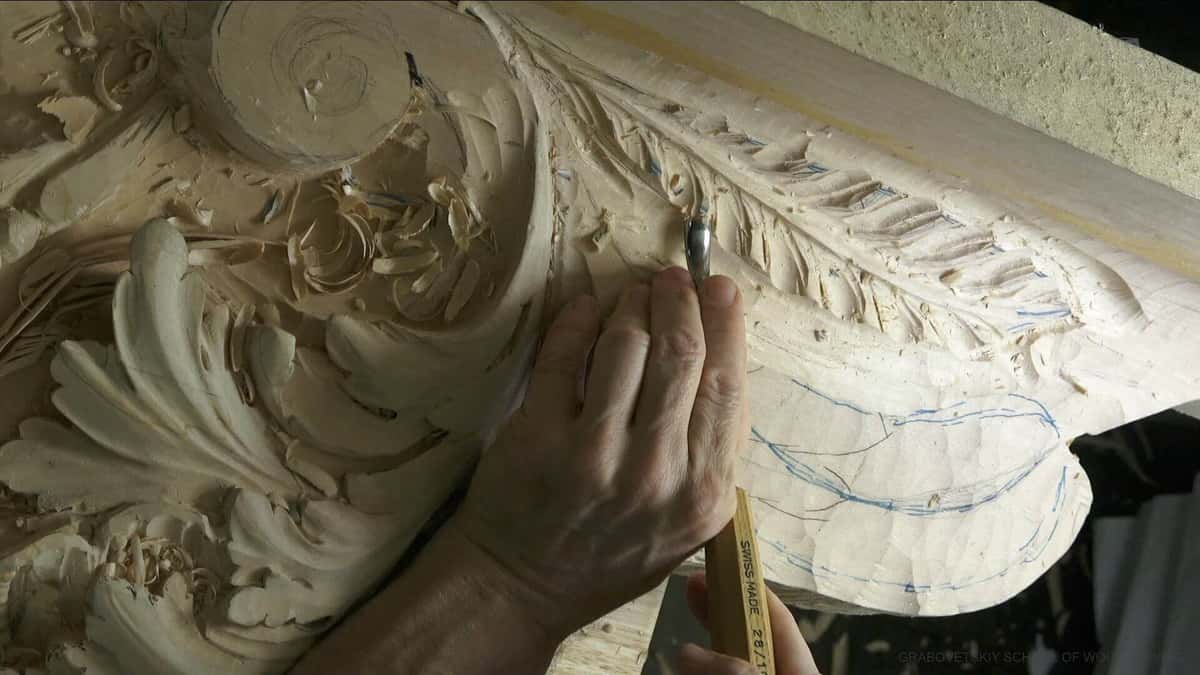A volute and leaf moulding under a steadying hand