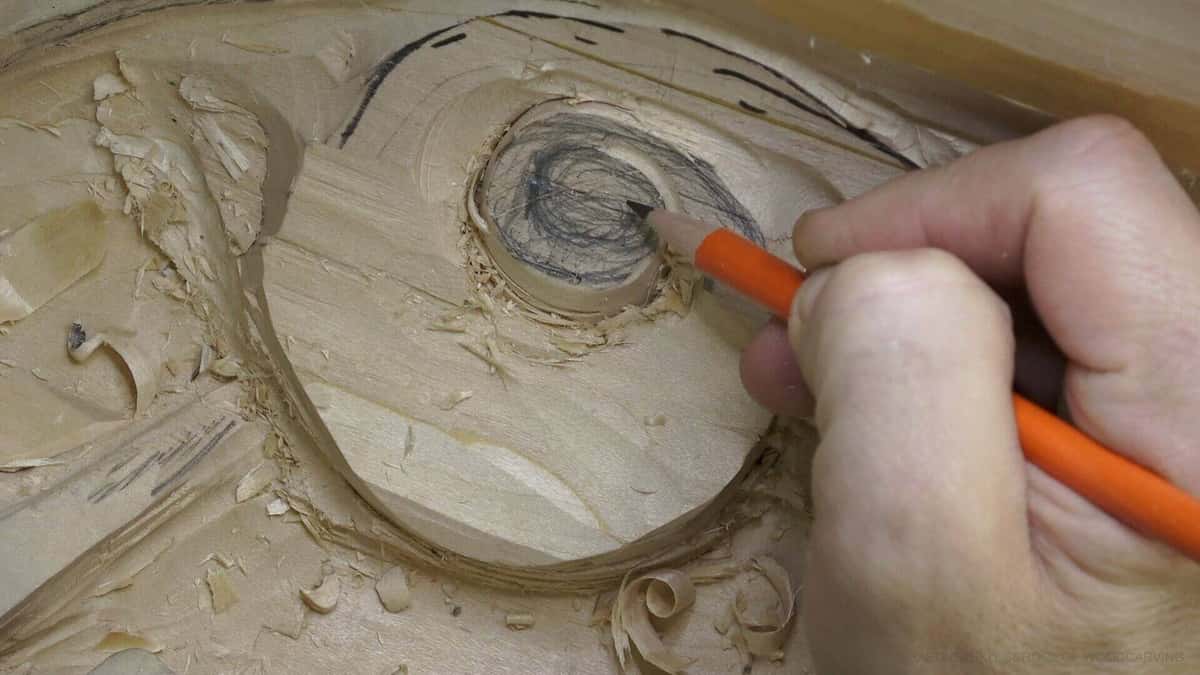 Orange pencil redrawing the spiral centre of a volute already sunk into basswood