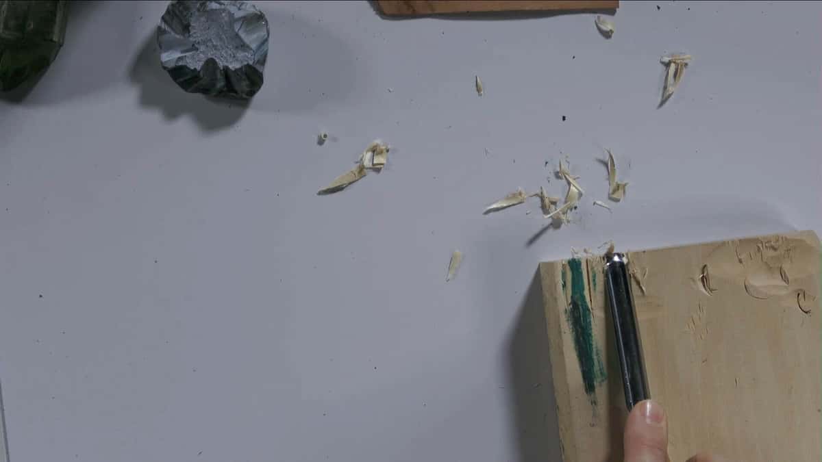 Freshly stropped gouge slicing a curl off a small basswood block, shavings scattered