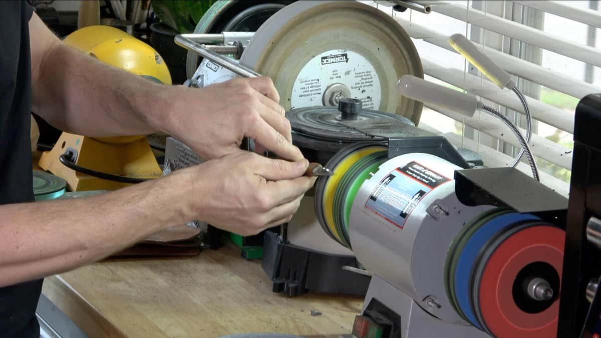 Hands buffing a gouge edge on a bench grinder wheel
