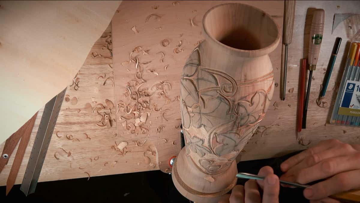 Turned vase blank with the leaf design drawn on and gouges laid out beside it.