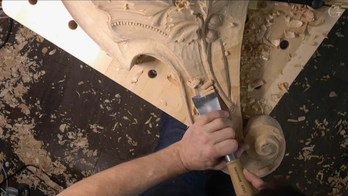 A wide Pfeil chisel stamped 2 by 50 taking background beside a carved volute on a big basswood panel
