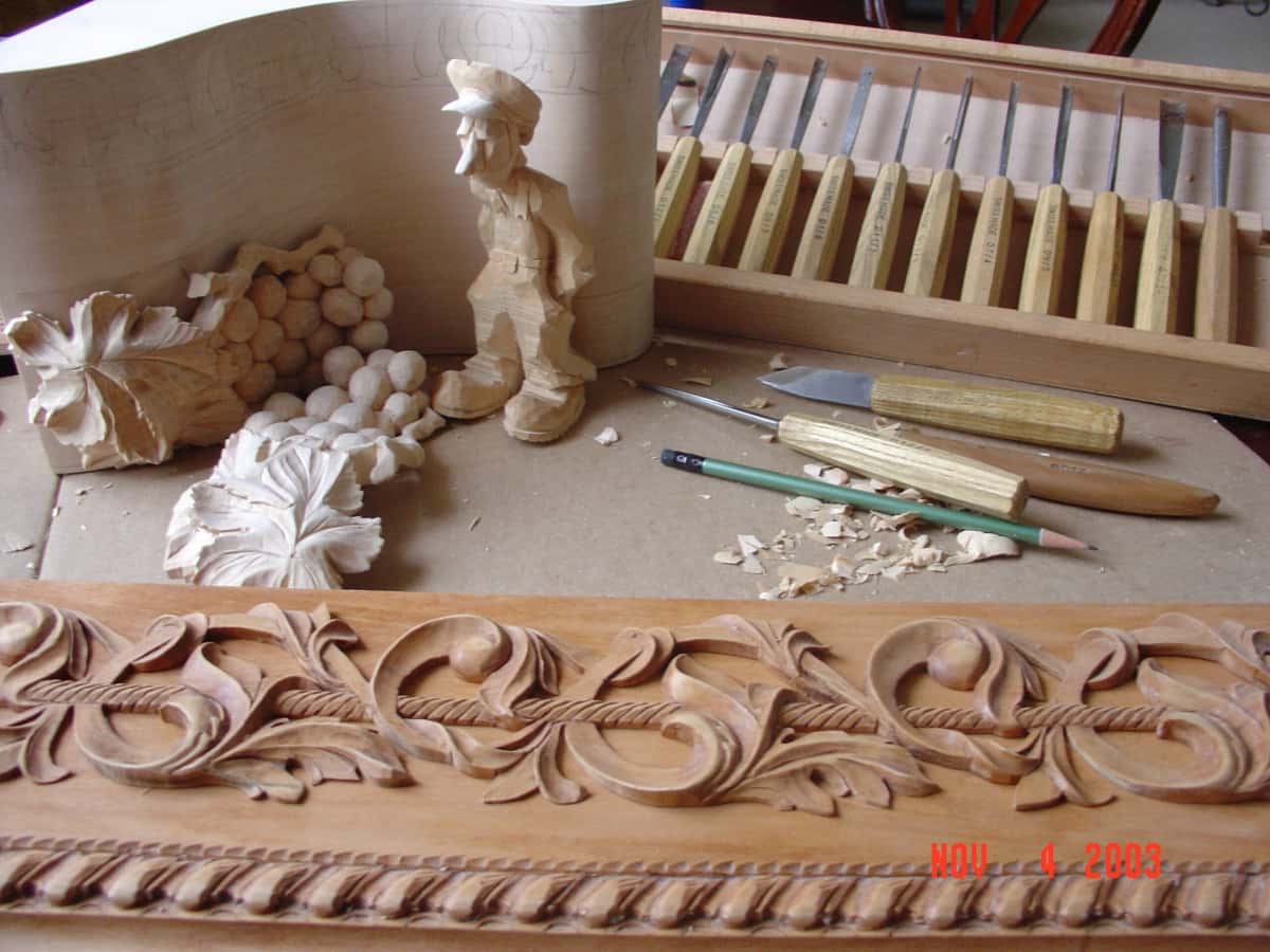 Homemade rack of gouges behind a carved acanthus moulding and a small carved figure