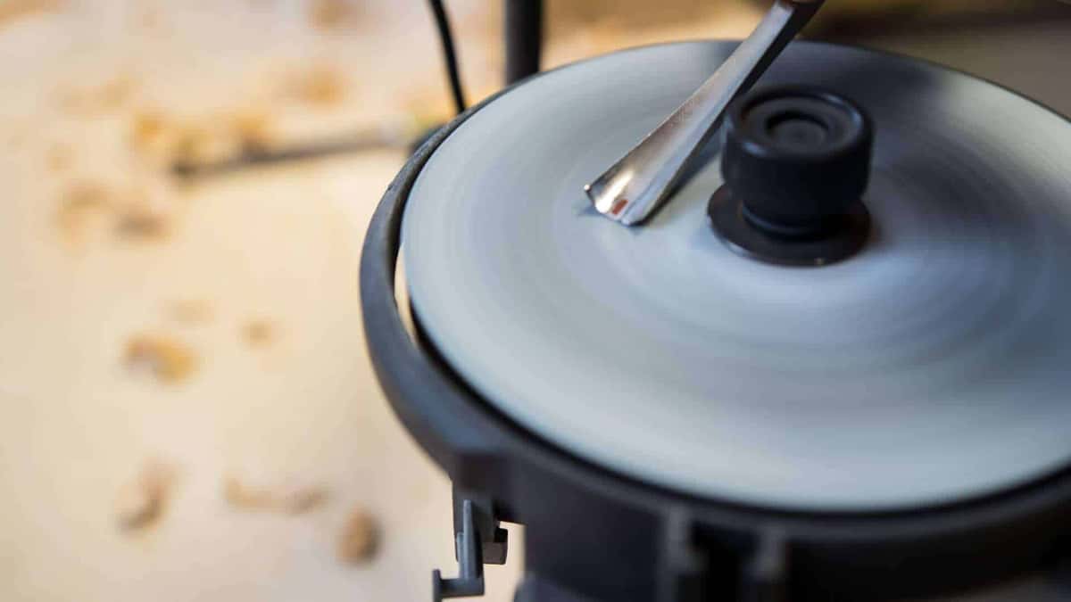 A carving gouge held against the spinning wheel of a sharpener