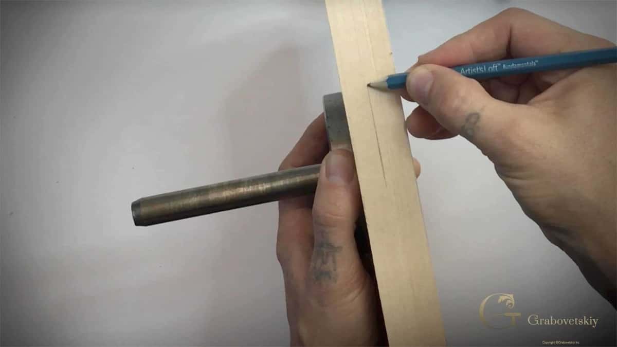 Pencil marking a line along a narrow strip of pale carving wood