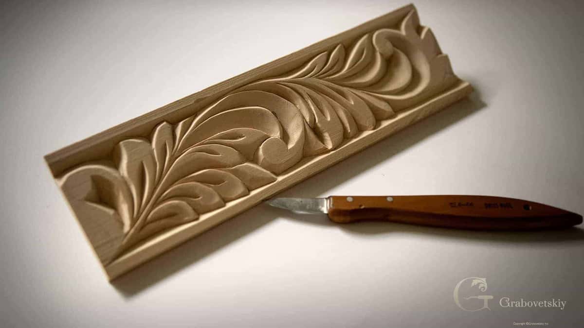 Carved basswood molding with a leaf running its length, beside the small knife that made it
