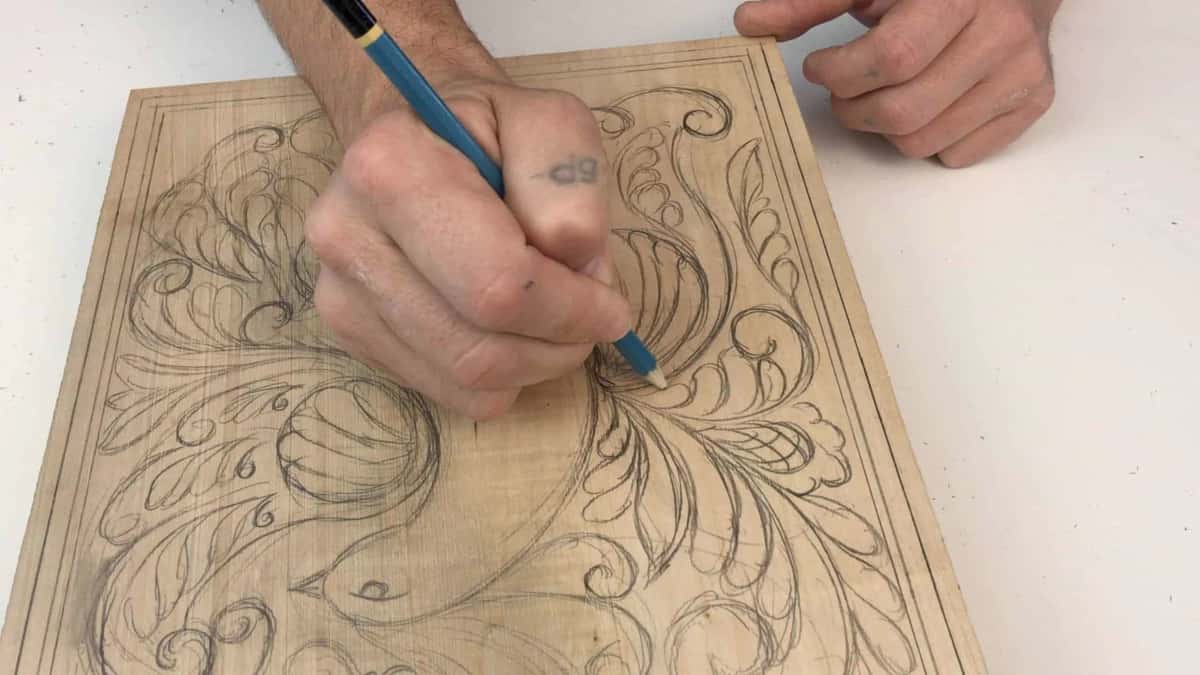 Blue pencil laying an acanthus design across a light board