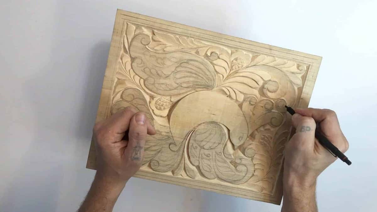 A black pencil goes back over a board already part carved