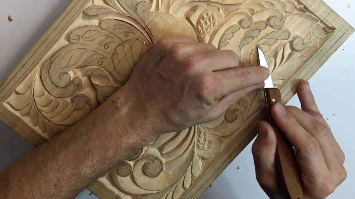 Both hands grip a single knife, fingers braced behind the blade rather than out in front of it