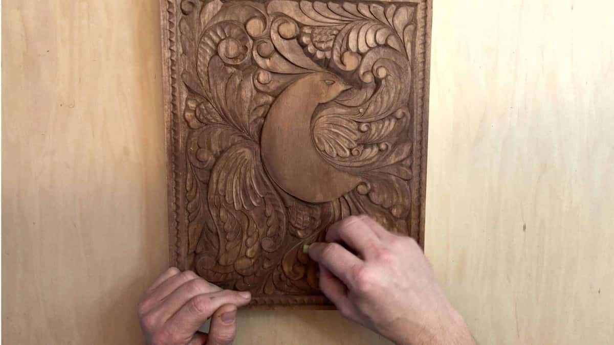 The finished bird panel, a deep even brown all over, held up flat against pale birch plywood