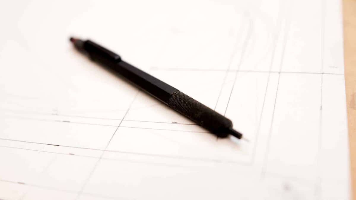 Construction lines ruled faintly across a sheet under a black mechanical pencil