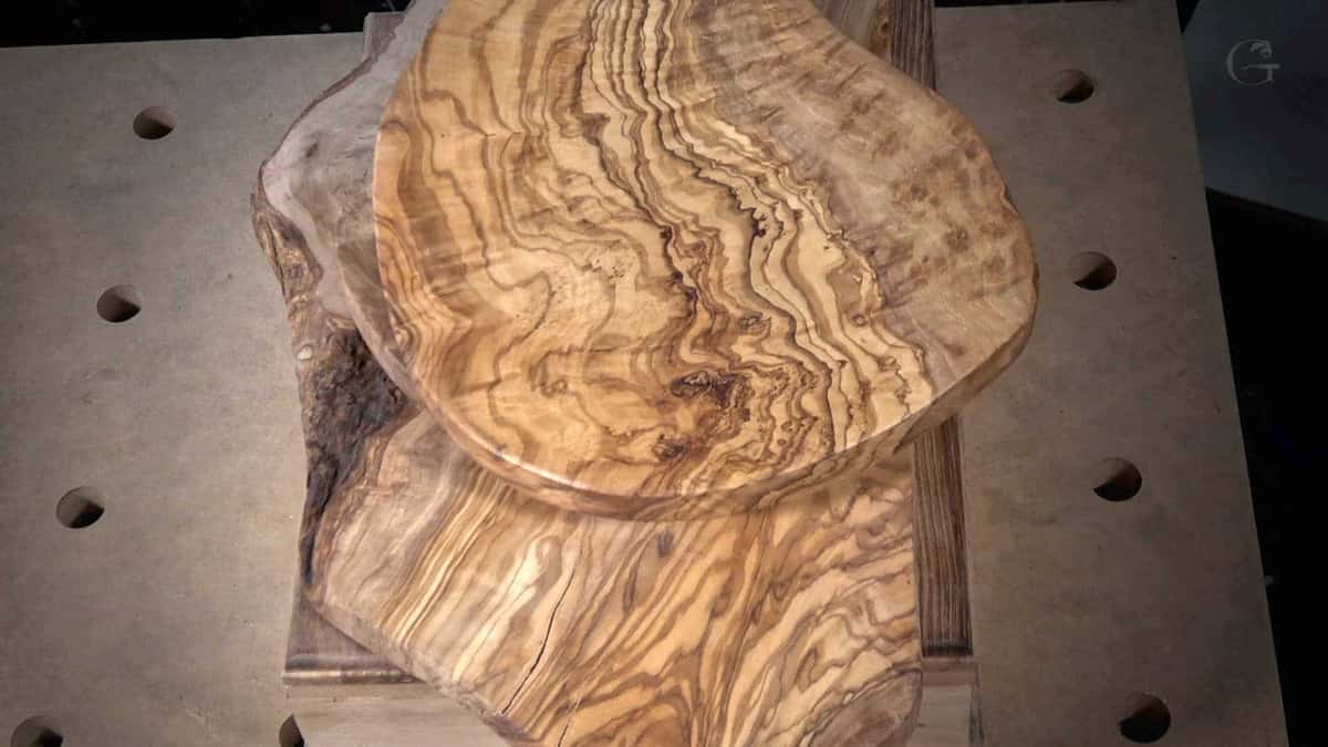 Swirling olive wood blank on a live edge slab, the kind of wild figure that fights a beginner gouge