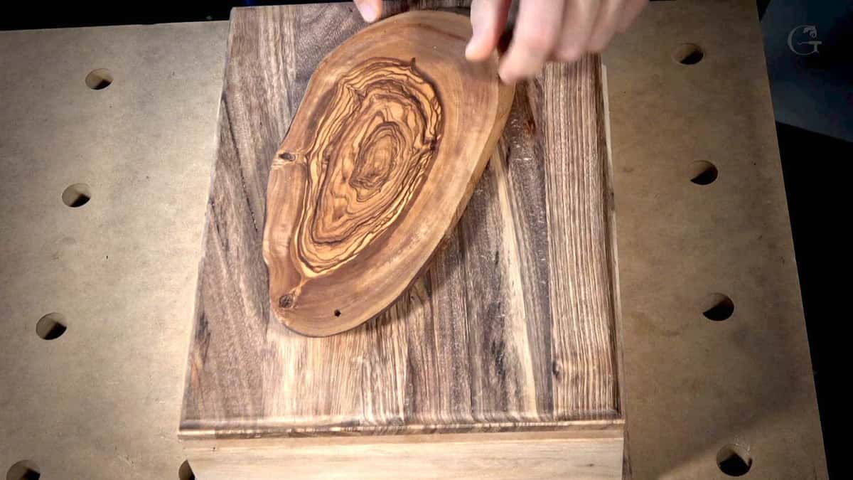 Small olive wood oval with tight swirling figure held above a box