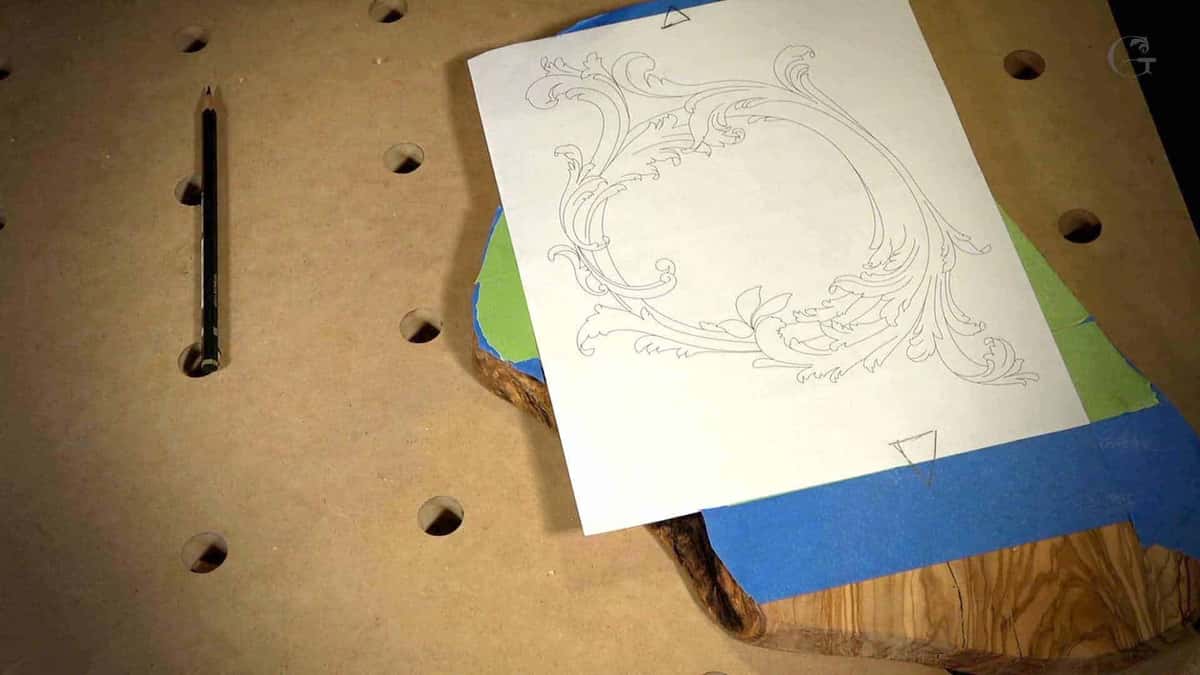 Paper pattern taped over a dark figured board on a dog hole bench top