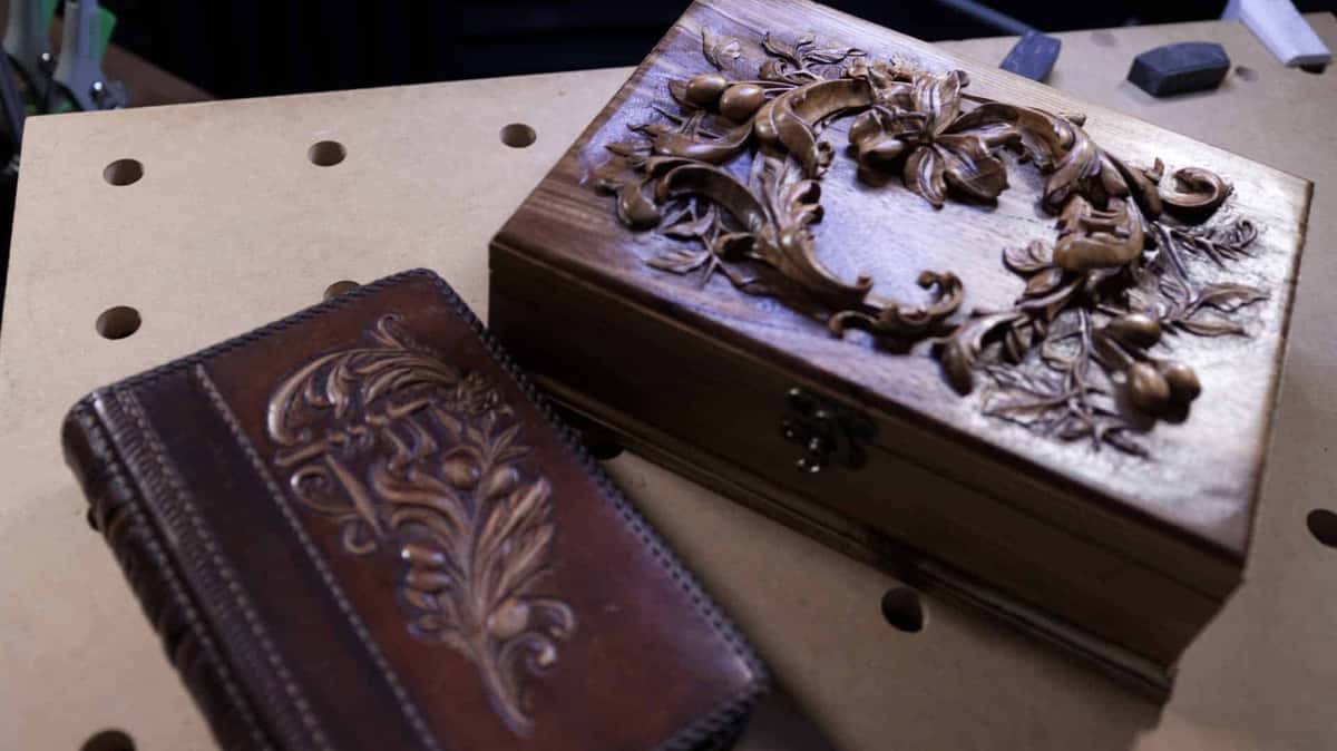 Brass clasp on a dark figured box beside the leather book it was carved for