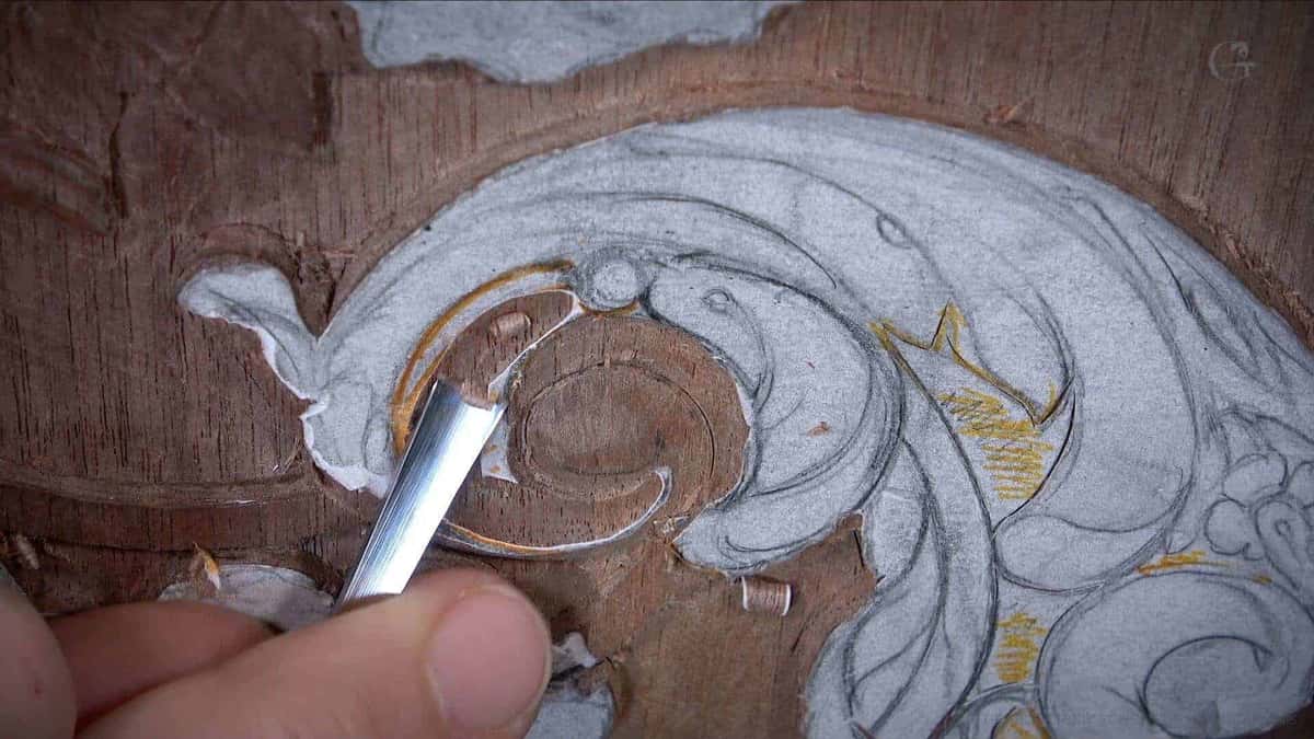 Straight grain crossing a brown walnut panel as a gouge lifts one scroll
