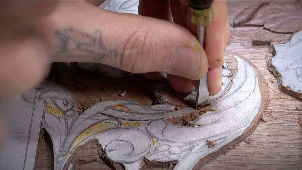 A small gouge easing into dense reddish walnut, the kind of timber that resists every pass