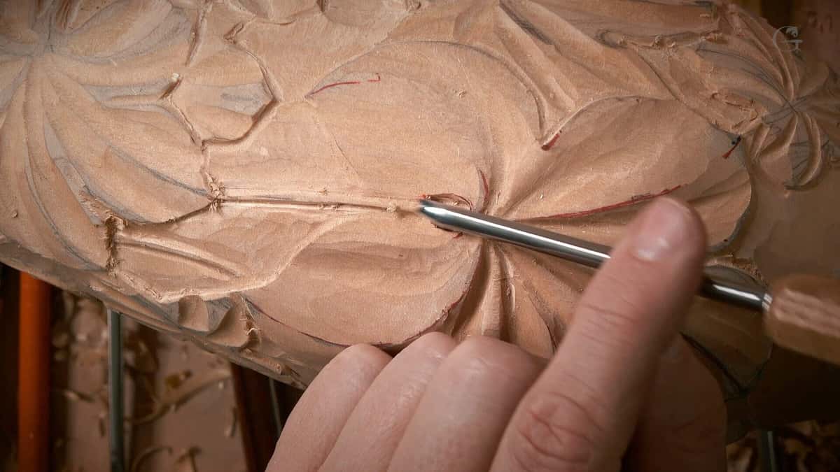 Warm toned grape leaves modeled in relief, tool tip resting in one flute