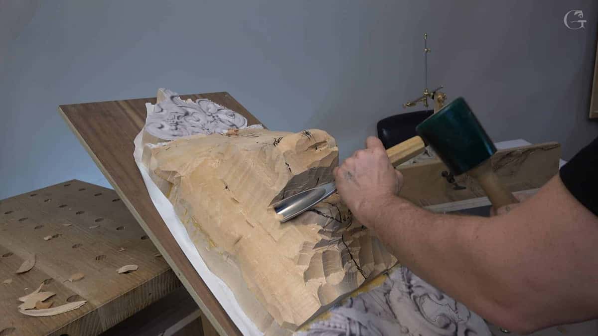 Green mallet driving a gouge into rough basswood blank