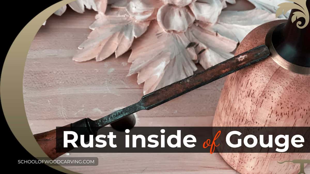 Rust pitting along the inside flute of an older carving gouge laid on a carved panel