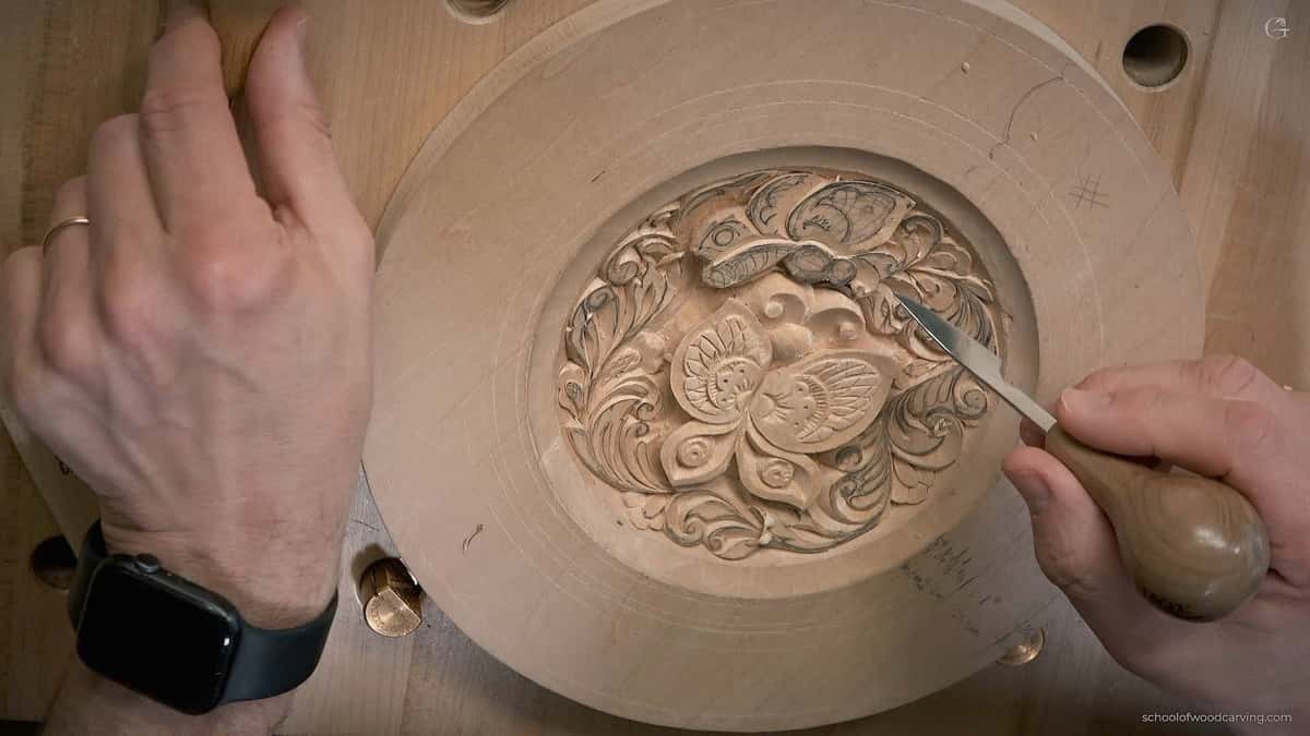 Small gouge working a dense floral medallion inside a turned plate
