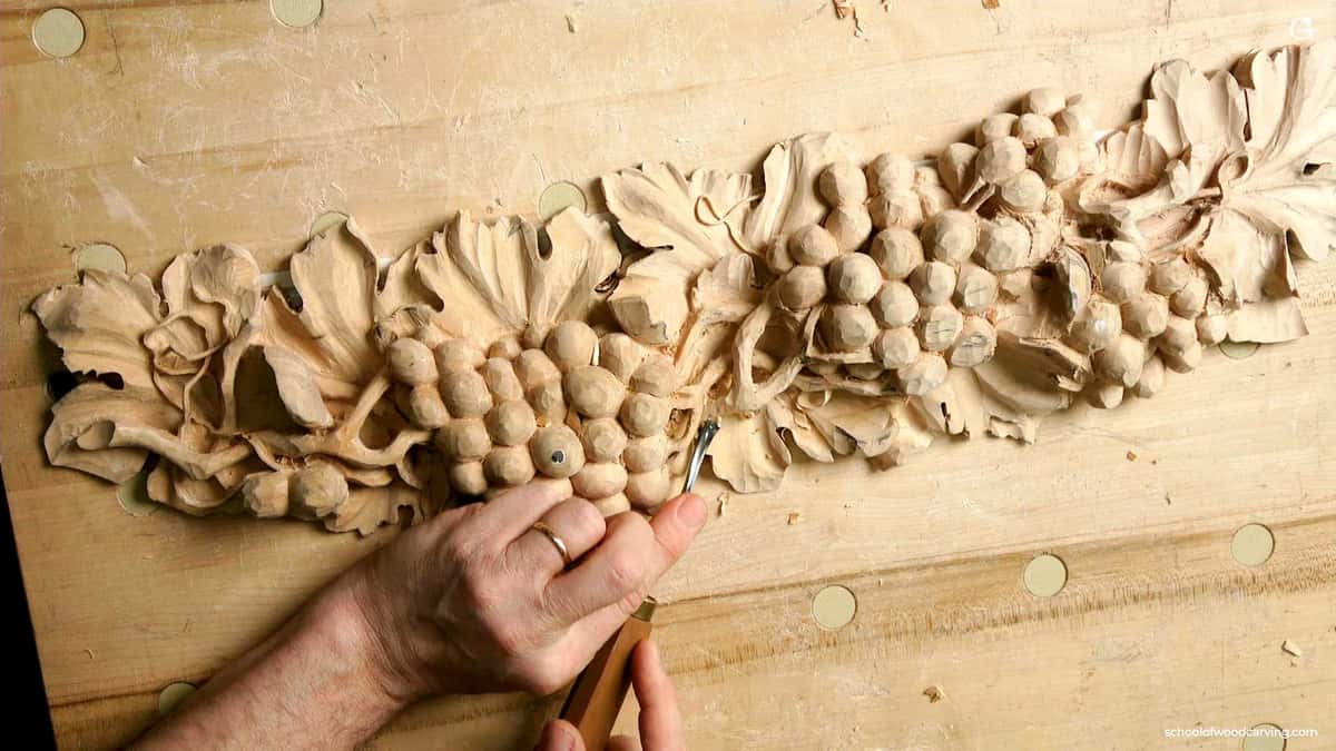 Long grape band carved along a wide board studded with round dog holes