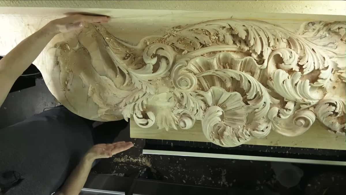 Deeply carved acanthus scroll relief with an open hand hovering just above the finished leaf work.