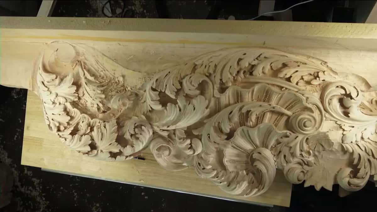 Wide view of the acanthus scroll relief carving laid across a wood workbench.