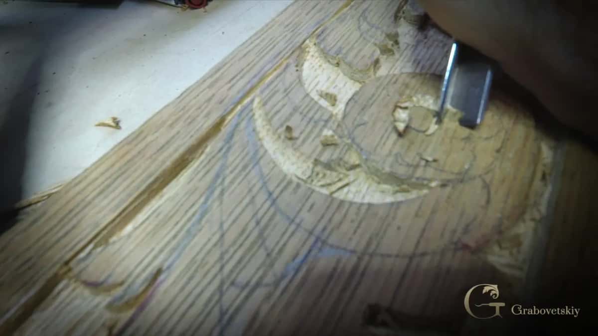 Heavy grain lines stripe the board like corduroy, with blue pencil curves drawn across them and a gouge at work.