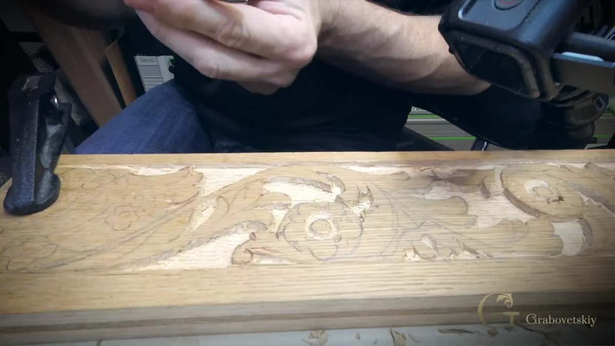 Seen end to end, the carved molding shows how the grain runs the length of the board under leaves and flowers.