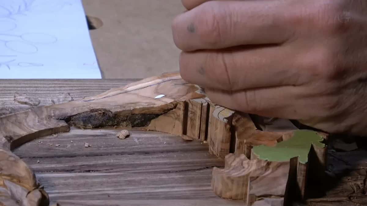 Rows of stop cuts leave ragged fibre standing between them, pale against the grey face of the same board.