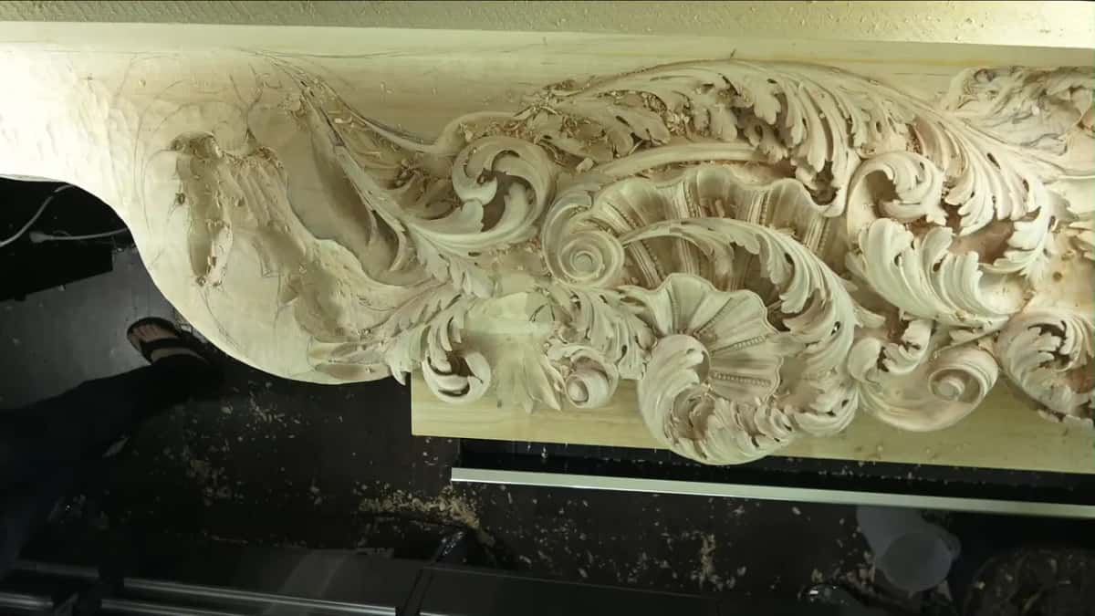 Scrolls and shells fill a long pale panel on the bench, with chips and dust spread on the dark floor.