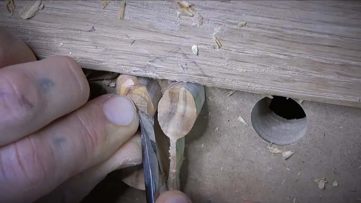 Carving tool pressed into a small wood piece close to the workbench surface.