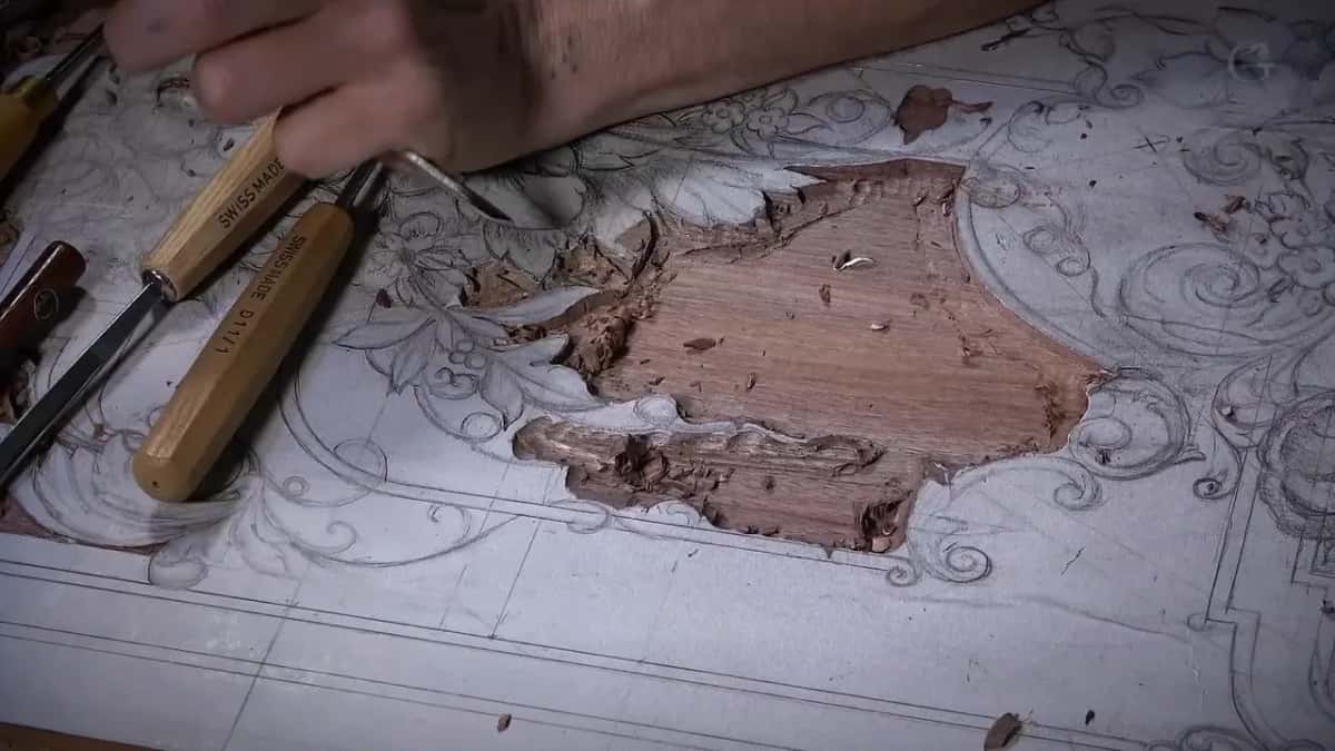 One area of a full-size pencil drawing chopped down to bare oak, two Swiss gouges resting alongside