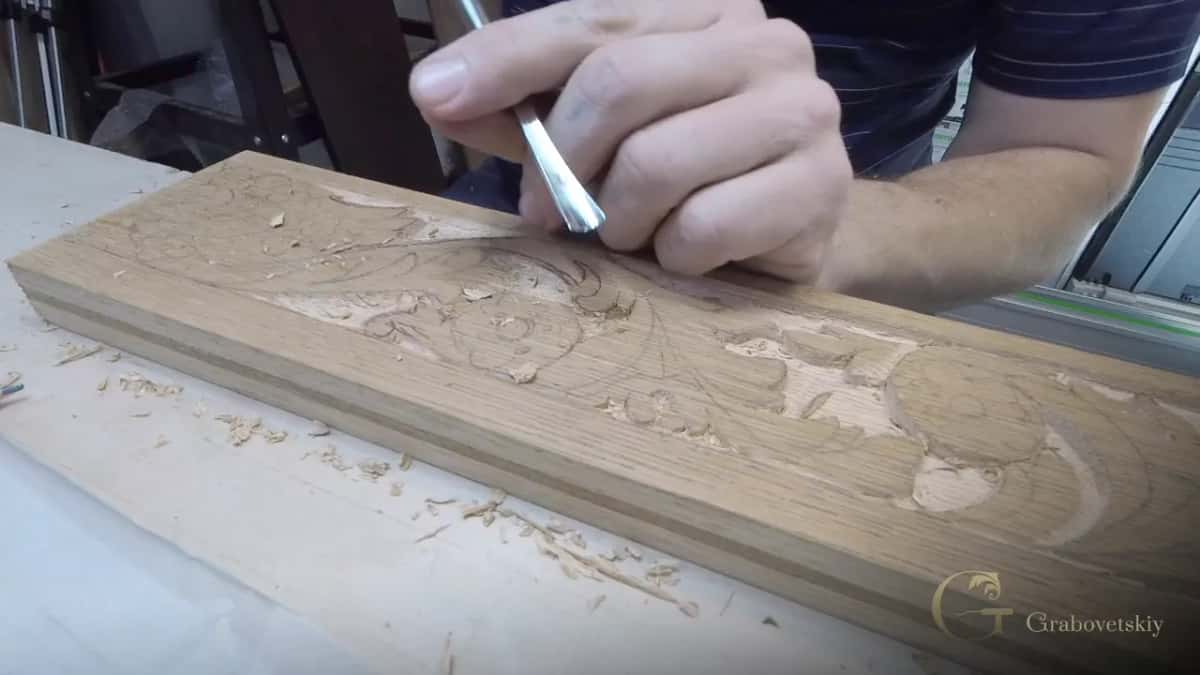 Chrome gouge in a closed fist starting the scroll drawn in pencil on an oak rail