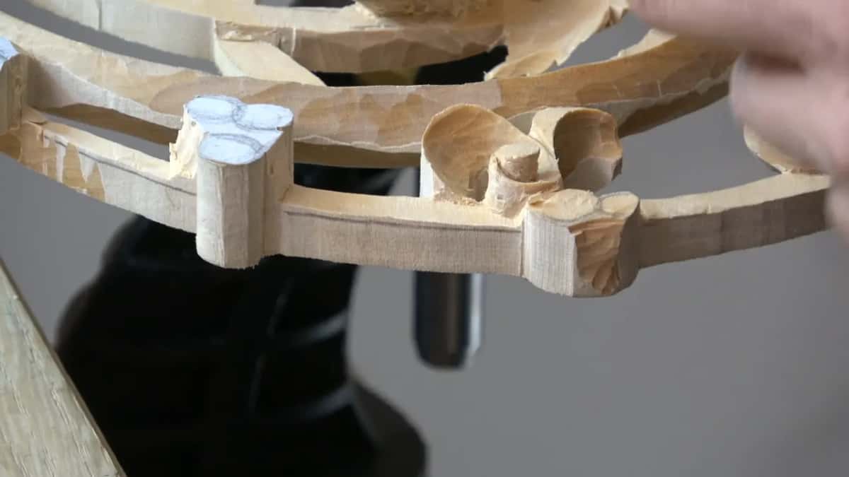 Roughed pierced wreath standing in the vise, thin curved rails and chalked round bosses waiting to be shaped