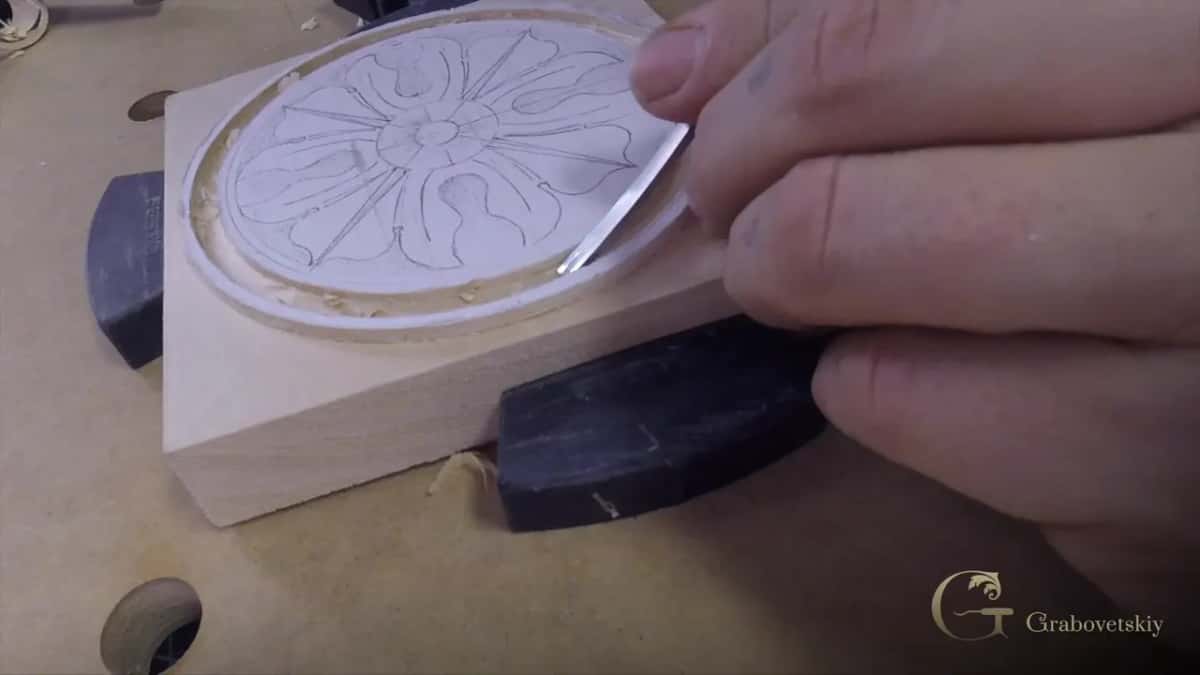 The rosette still drawn in pencil, its outer ring already lowered, a skew blade slicing along the circle